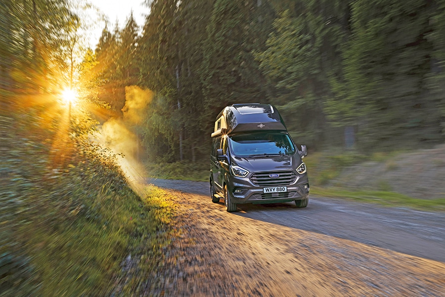 Schwarzer Campervan Nugget auf einer Waldstraße