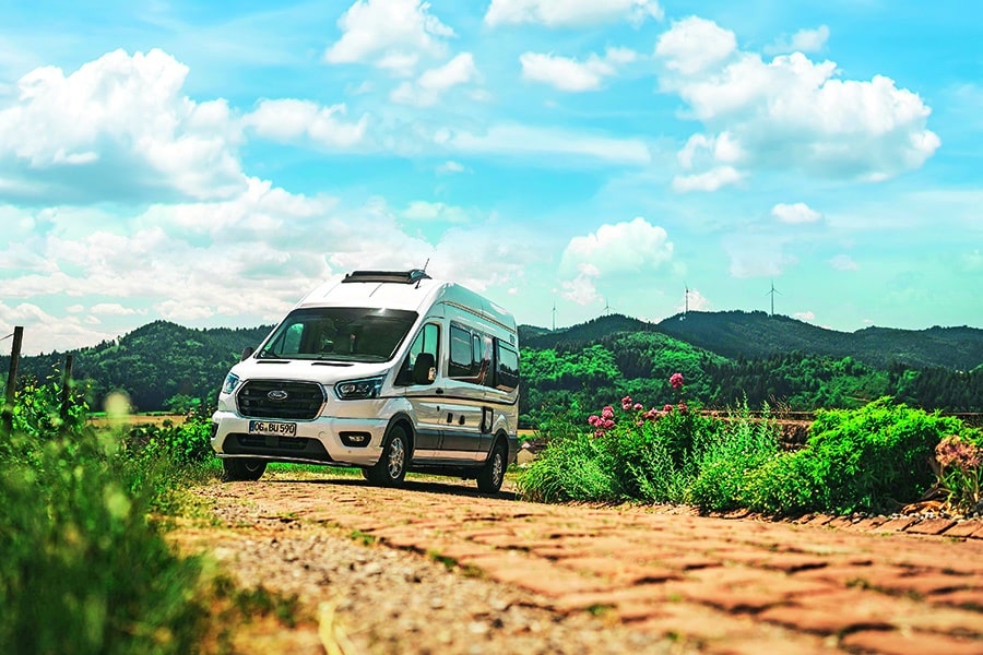 Marktübersicht Ford Transit Camper: Bürstner Lineo auf Feldweg in einer bergigen Gegend fotografiert