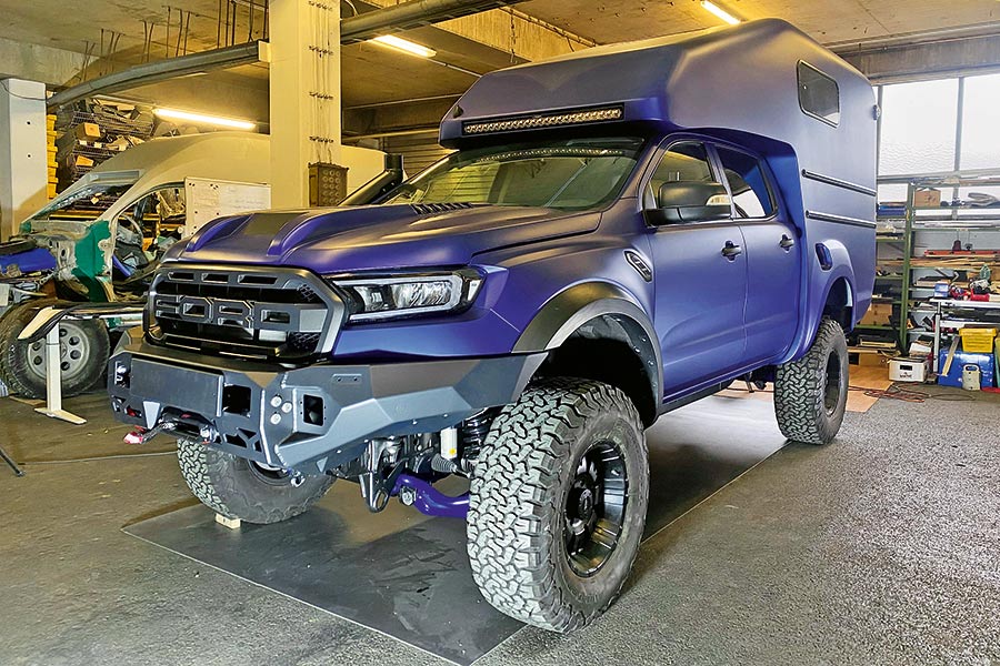 Blauer Pick-up mit gleichfarbiger Alkoven-Wohnkabine in einer Halle