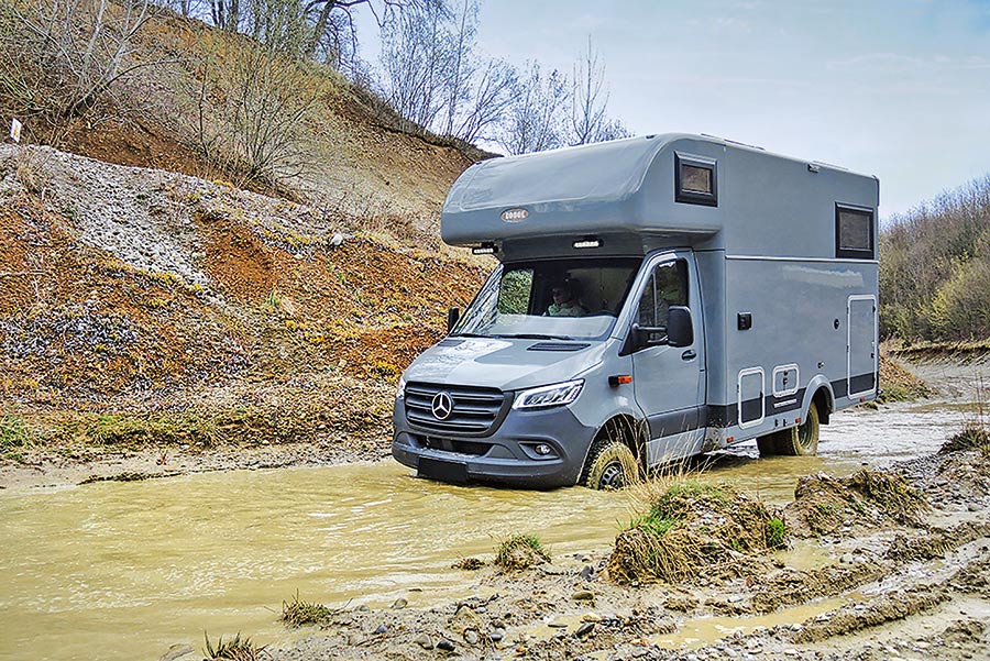 Alkoven-Expeditionsmobil Robel K 670 HLB im Offroad-Park bei Biberach fährt durch schlammiges Wasser