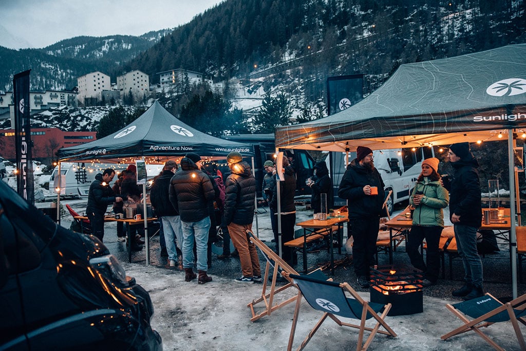 Geselliges Zusammensein unter mit Lichterketten beleuchteten Pavillions auf dem schneebedeckten Campingplatz