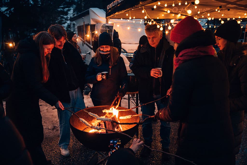 EIne Gruppe Menschen grillt Stockbrot über einer Feuerschale