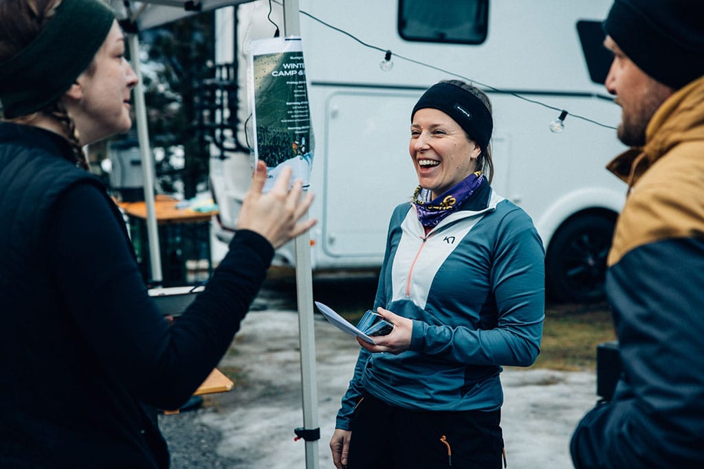 Zwei Frauen und ein Mann unterhalten sich auf dem Campingplatz