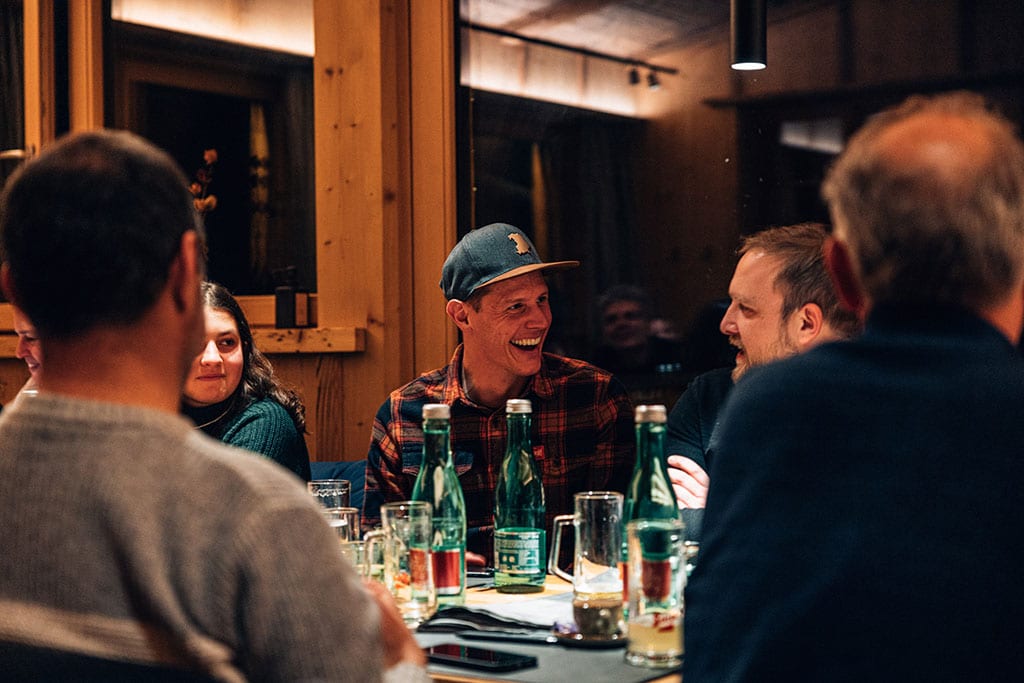 Mehrere Menschen sitzen beim Abendessen zusammen in einer Hütte