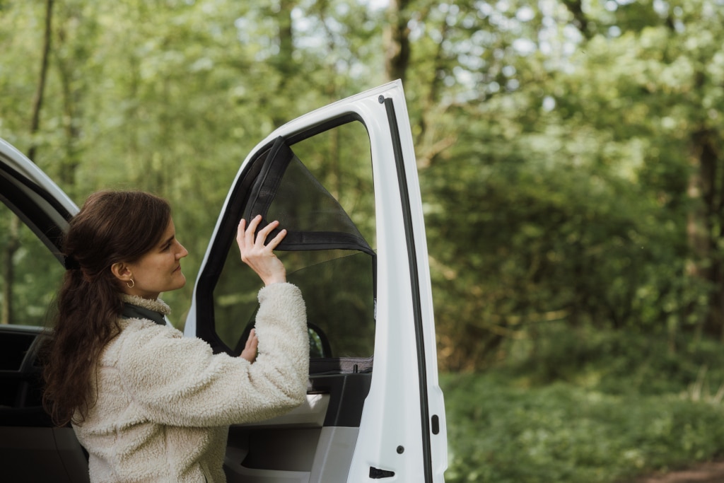 Zubehör für den Camping-Sommer: Frau bringt Magnetmoskitonetz an Camper-Türe an.