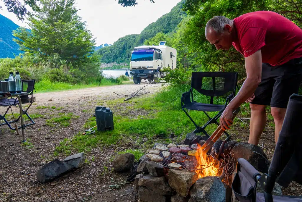 Mann am Lagerfeuer, im Hintergrund steht das Expeditionsfahrzeug