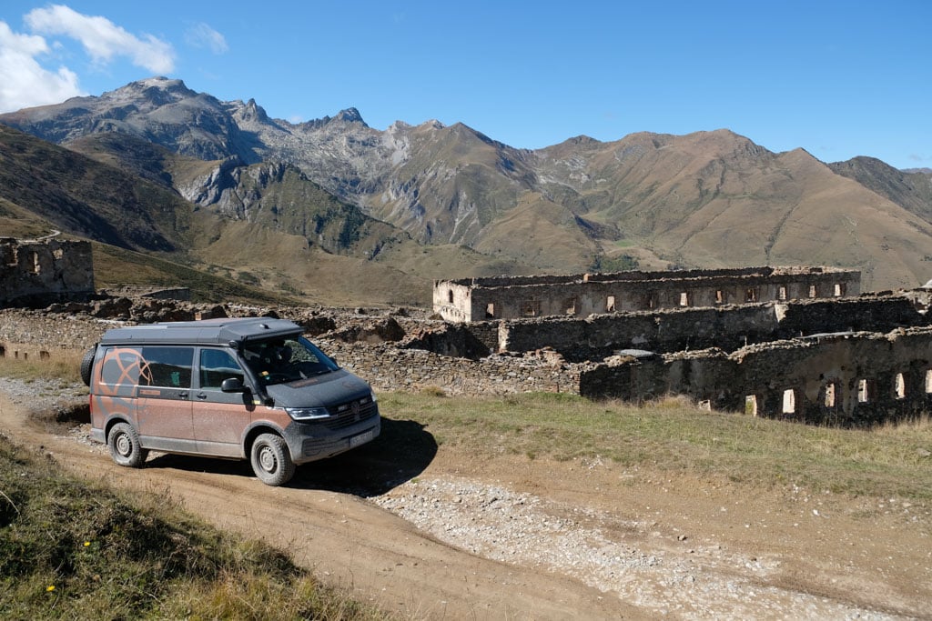 Dunkler VW-Bus auf einer Offroad-Piste in bergiger Landschaft