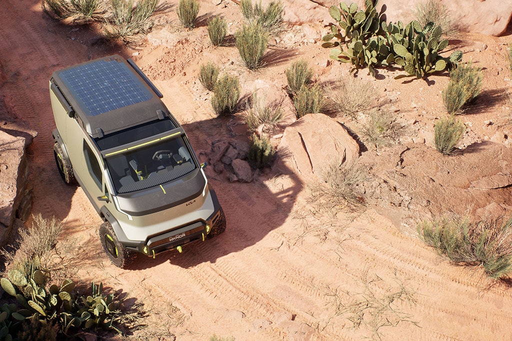 Luftaufnahme eines Fahrzeugs mit Solarpanels auf dem Dach in wüstenartiger Landschaft