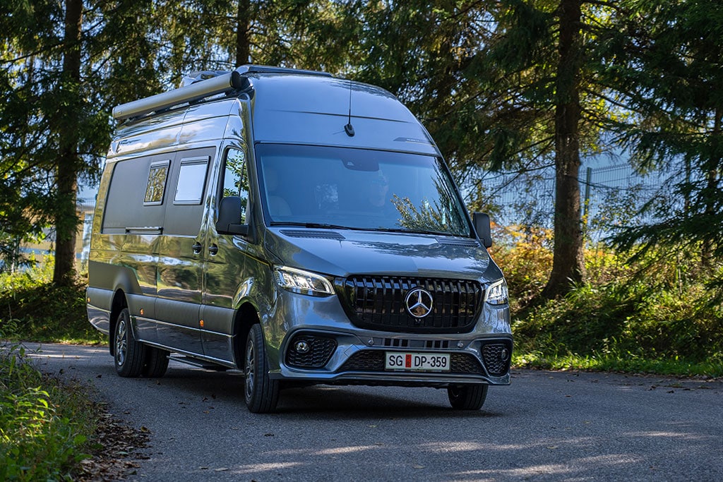 Dunkelgrauer Mercedes-Benz Sprinter mit Markise auf einer Landstraße