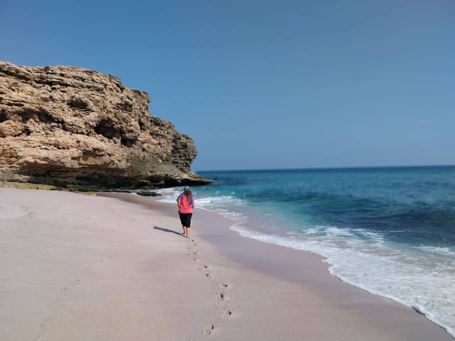 Eine Person läuft am Sandstrand am Meer entlang