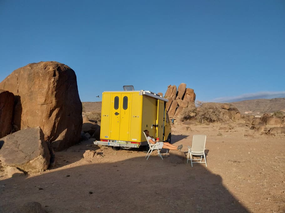 Gelber Camping-Postbus neben einigen Felsen in der Wüste